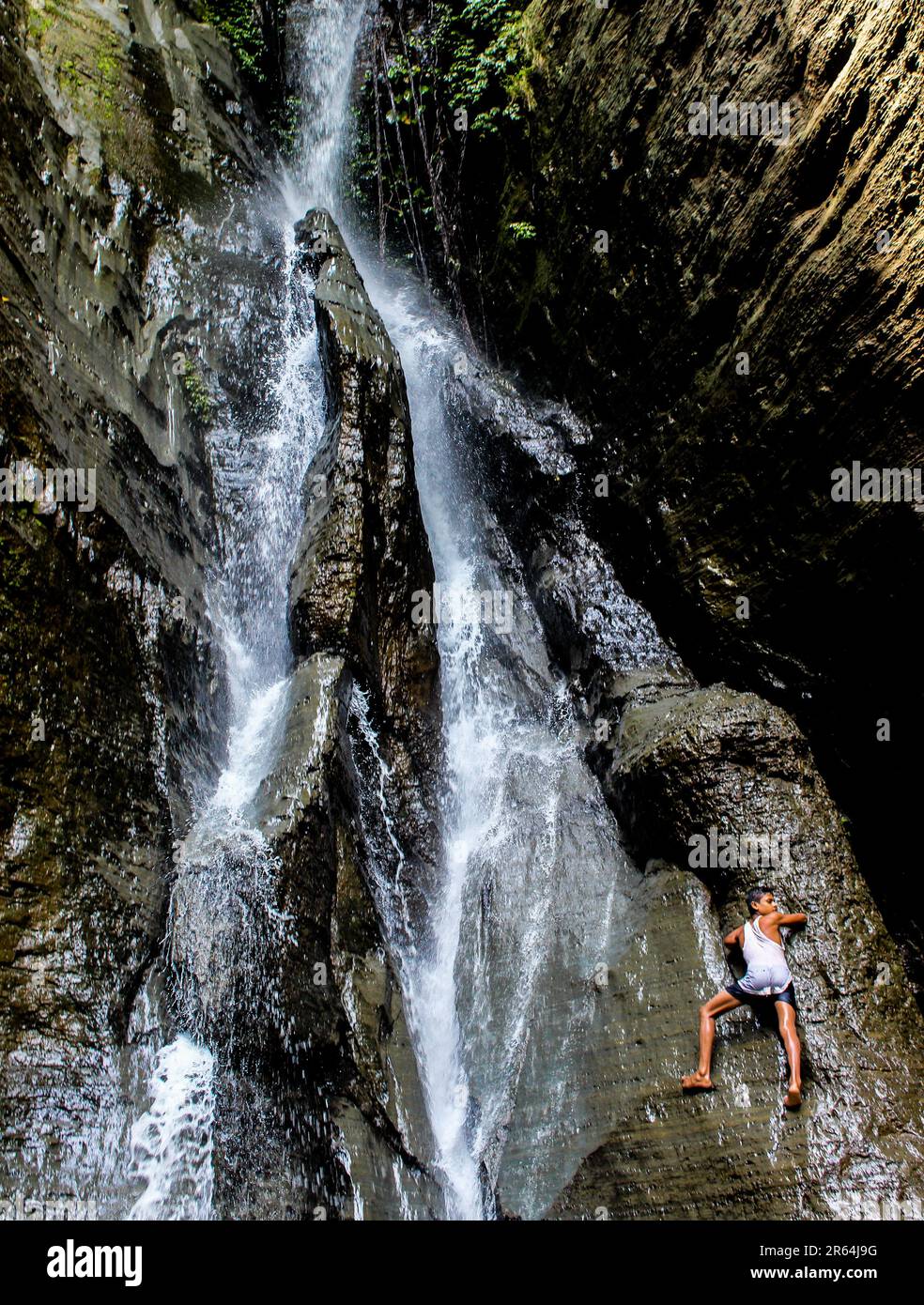 Spiderman puntato. Un ragazzo sale su una collina con una bella cascata. Foto Stock