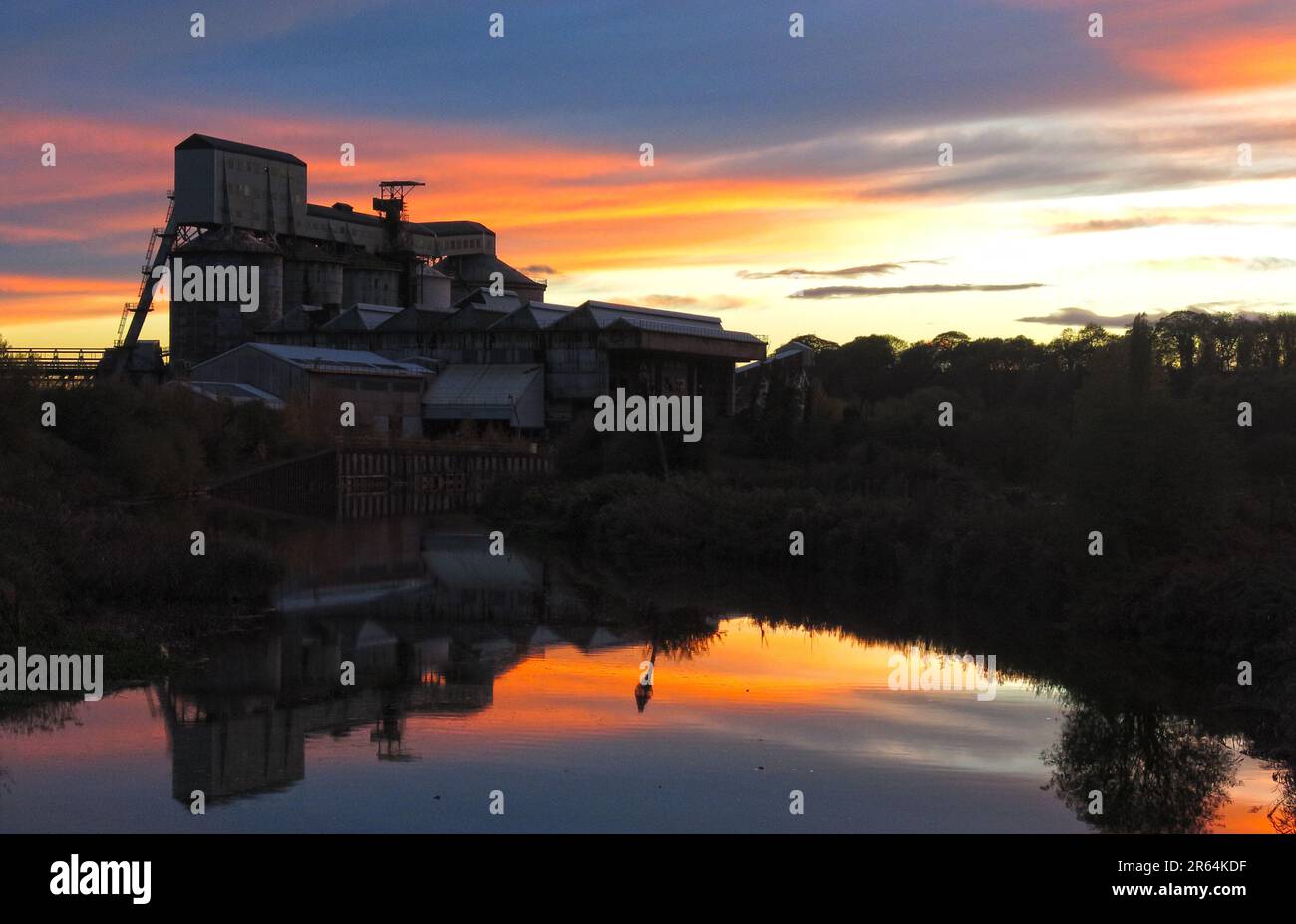 Tramonto sulle ex opere chimiche ICI a Northwich, riflesso nelle acque calme lungo il fiume Weaver, illustrando il patrimonio industriale britannico Foto Stock