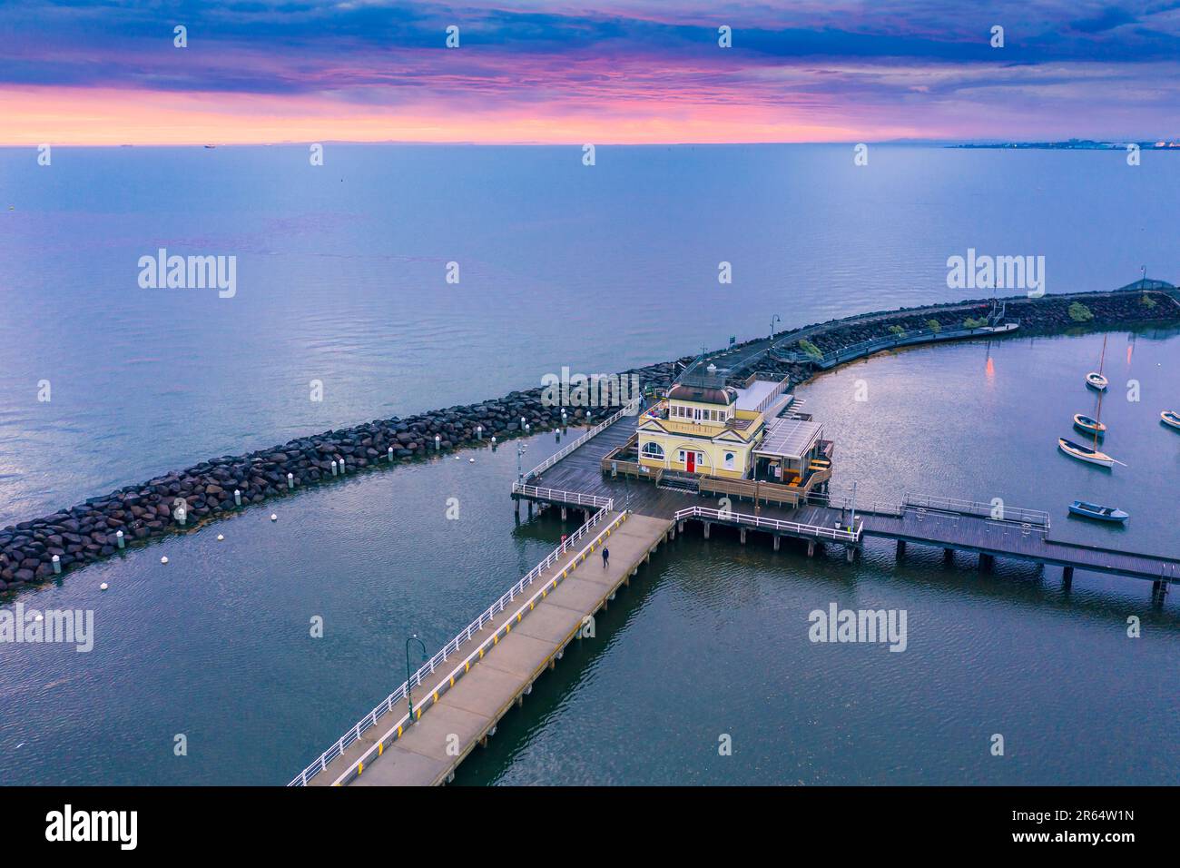 Vista aerea di un padiglione su un molo all'interno di un frangiflutti con un cielo colorato al tramonto in lontananza a Sandringham a Melbourne, Victoria, Australia. Foto Stock