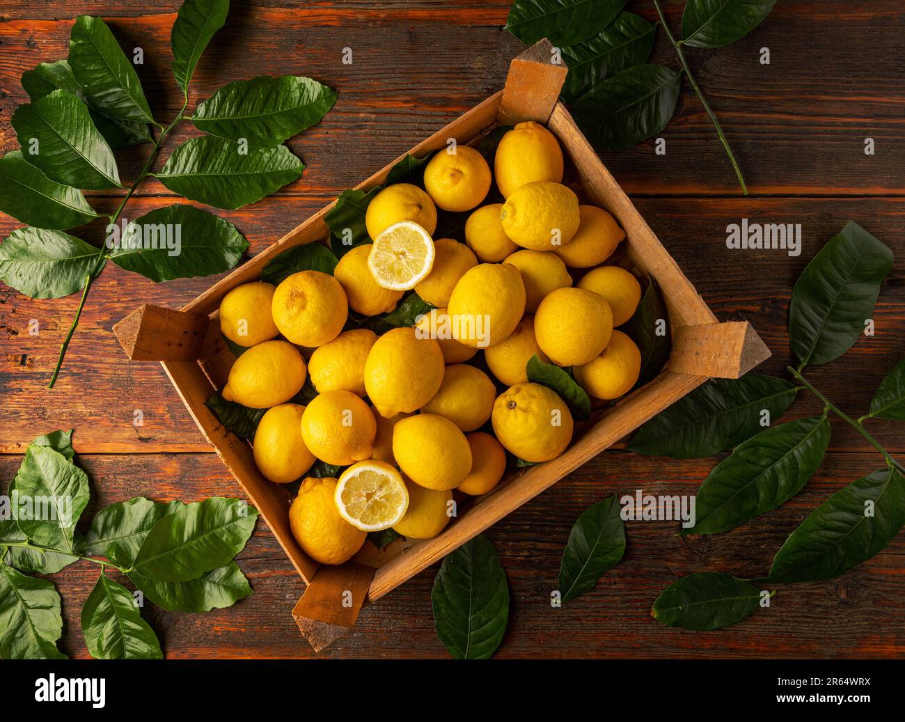 Vista dall'alto di limoni maturi e pezzi tagliati in scatola di legno Foto Stock