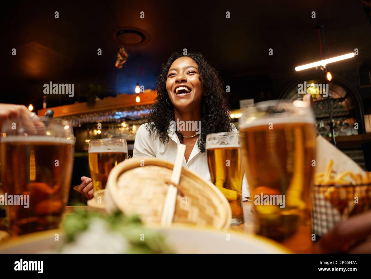 Primo piano di un felice gruppo di amici multirazziali giovani in abbigliamento informale che cenano al bar Foto Stock