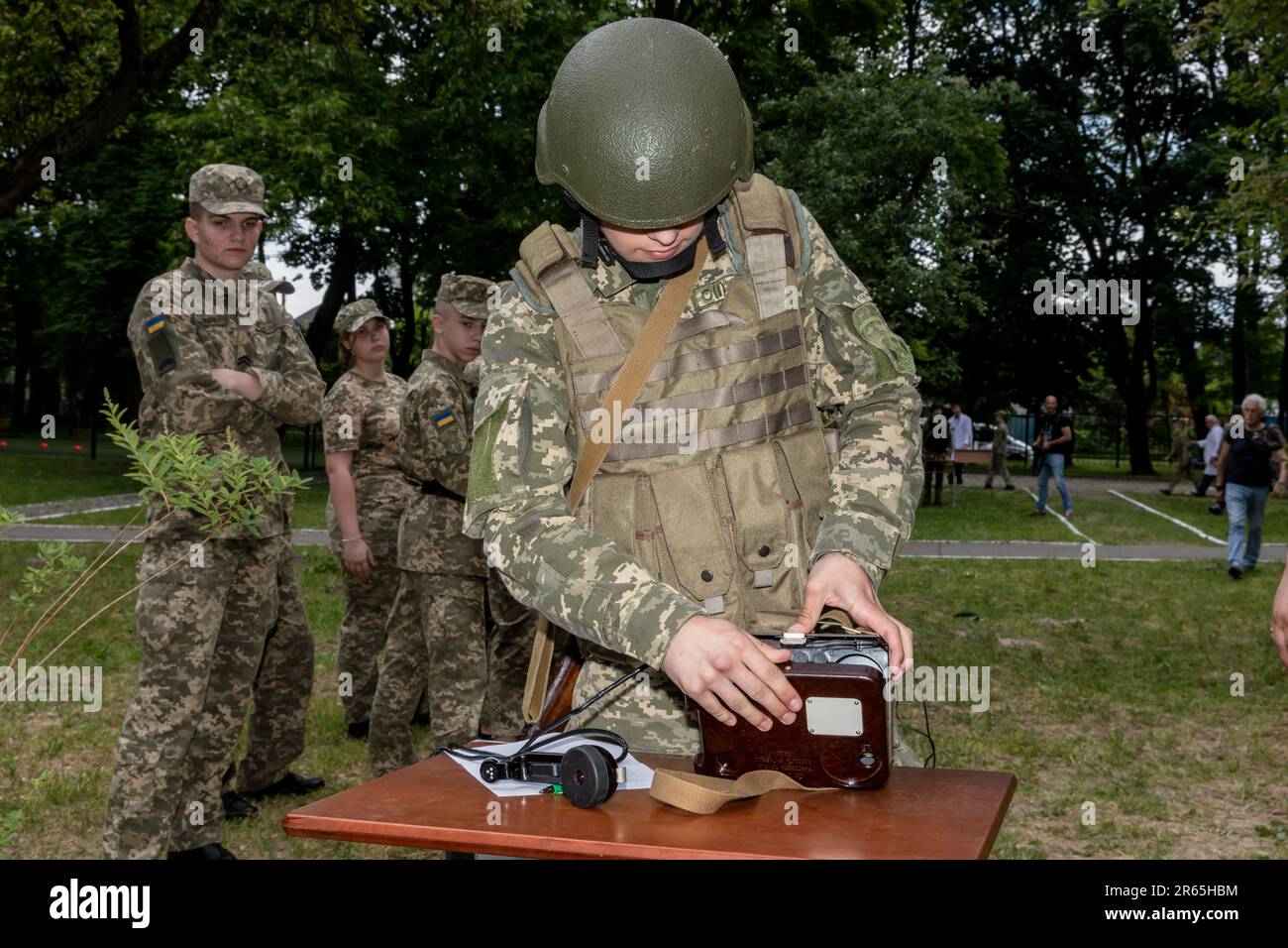 Un cadetto illustra le tecniche radio del palmare. La più grande missione militare di Kyiv tra i bambini cadetti ebbe luogo. Oltre 400 scolari hanno partecipato, competendo nel tempo e nelle abilità in 10 sedi. La sede di Minefield è stata preparata dalla Guardia Nazionale dell'Ucraina, con medici militari che organizzano una formazione medica tattica. Presso la sede della rinascita aerea, i droni sono stati lanciati in aria. Gli scolari stavano assemblando armi, scendendo al riparo della bomba e indossando attrezzature anti-radiazioni e anti-chimiche. Una cucina da campo era aperta per i bambini. Foto Stock