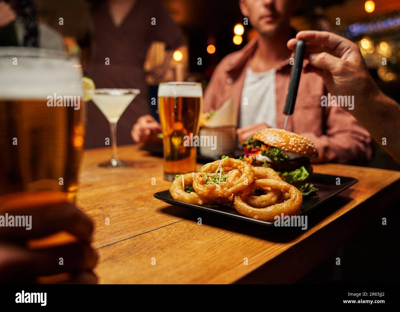 Primo piano di giovani amici multirazziali in abbigliamento casual gustando fast food e bevande al ristorante Foto Stock