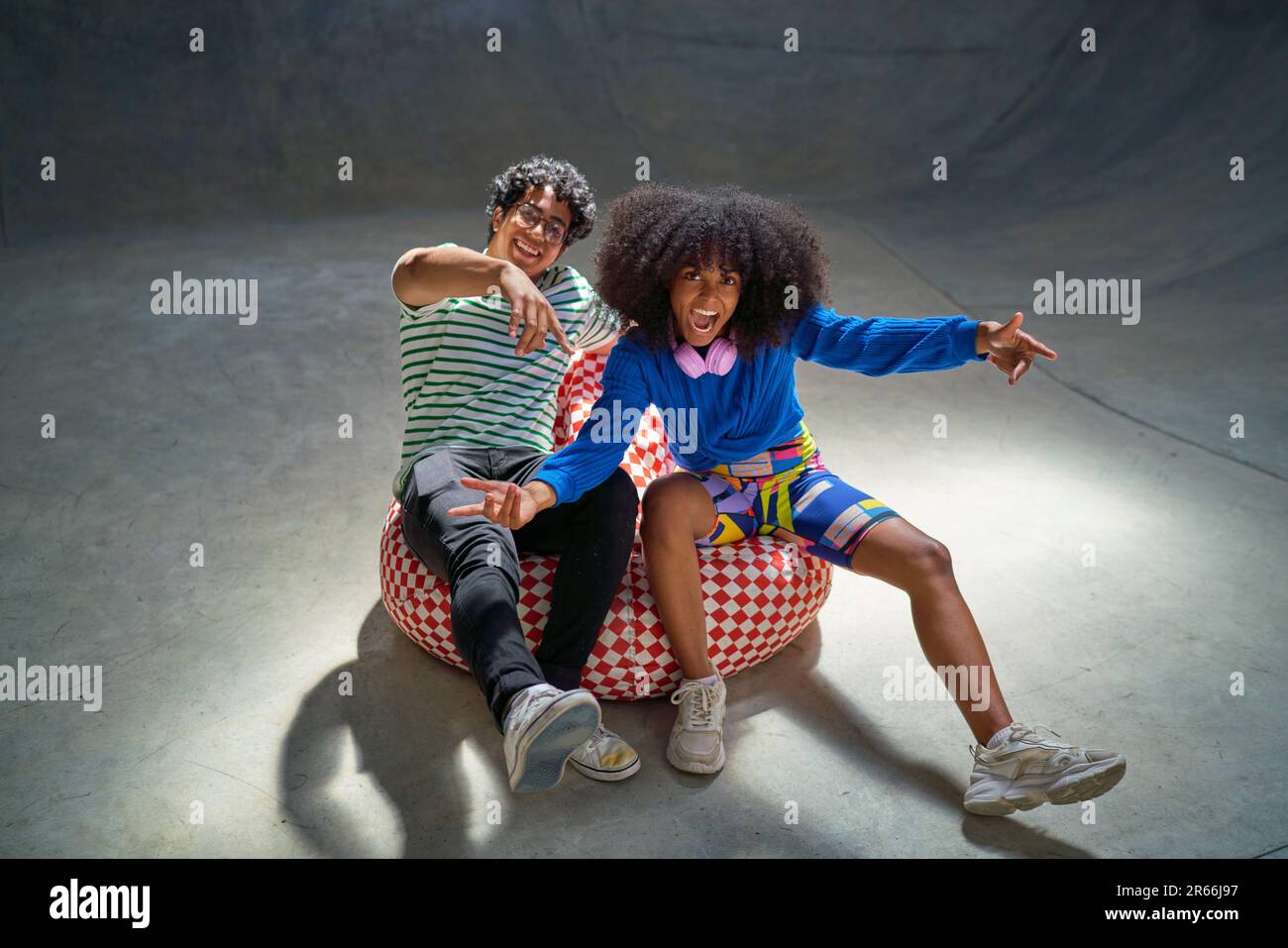 Ritratto cool, entusiasta giovani amici gesturing su sedia borsa fagiolo Foto Stock