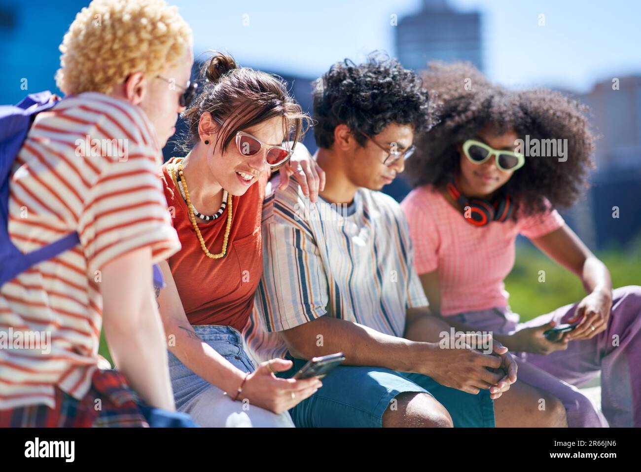 Giovani amici che usano smartphone in città soleggiata Foto Stock