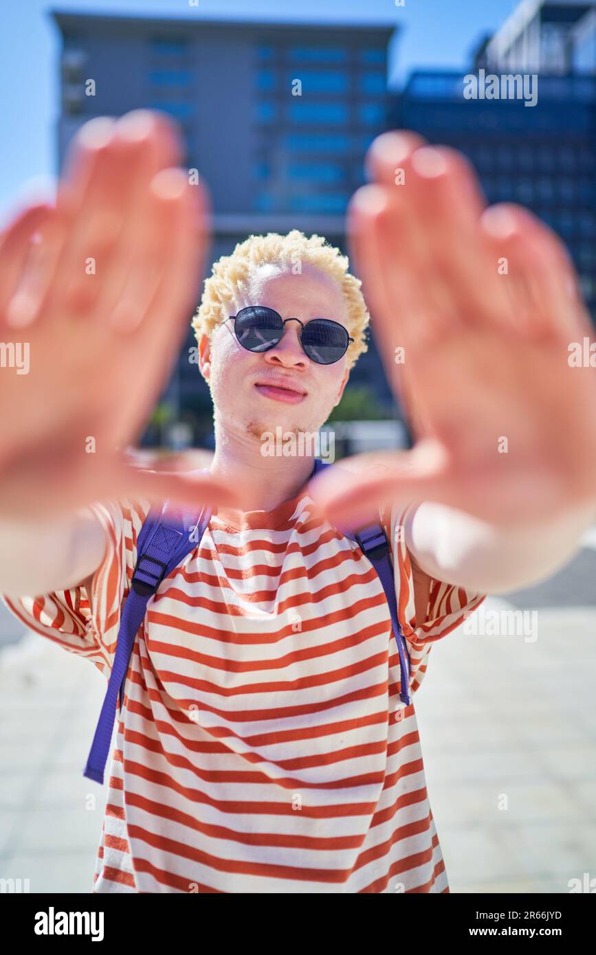 Ritratto fresco giovane uomo gestante dito cornice in città soleggiata Foto Stock