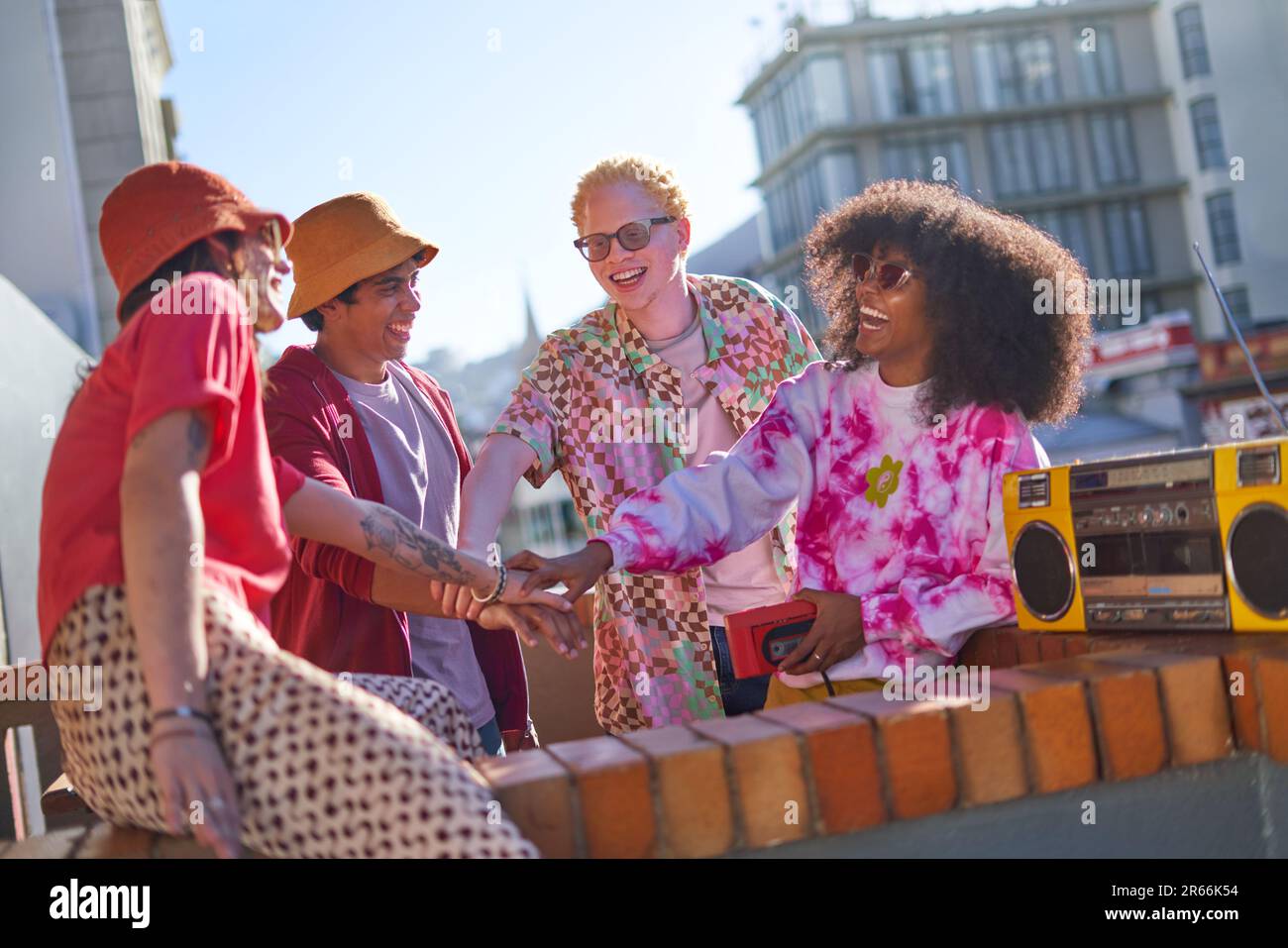 Felici i giovani amici con boom box che si unisce alle mani sul tetto Foto Stock