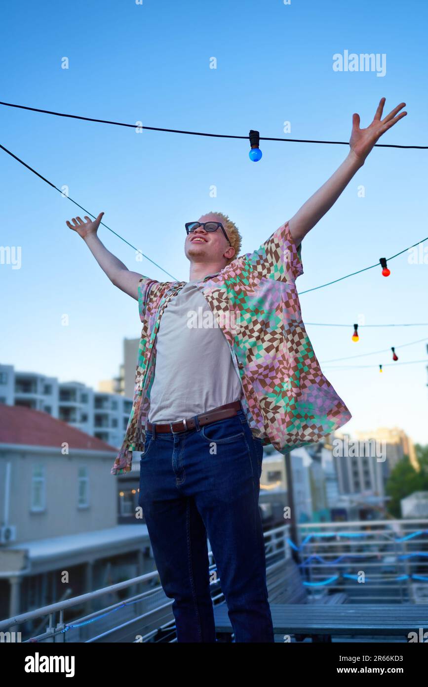 Ritratto giovane felice uomo con le braccia sollevate sul tetto urbano Foto Stock