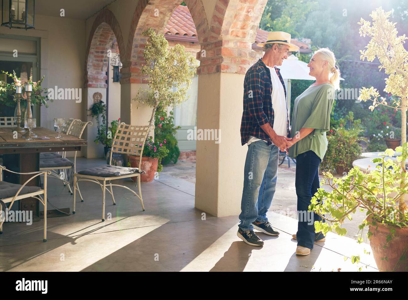 Felice coppia anziana che tiene le mani sul patio soleggiata villa Foto Stock