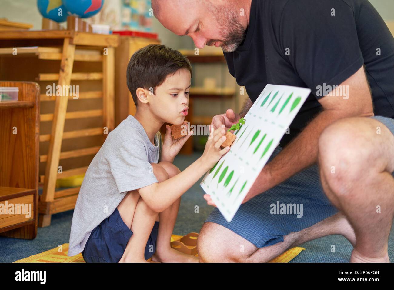 Padre e figlio con la sindrome di Down imparando a conoscere le piante in casa Foto Stock