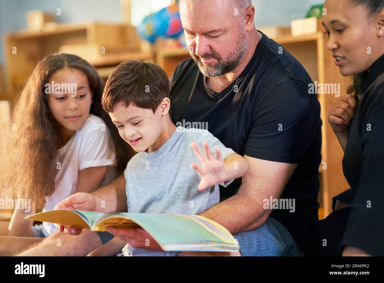 Ragazzo con sindrome Down leggere libro con la famiglia a casa Foto Stock