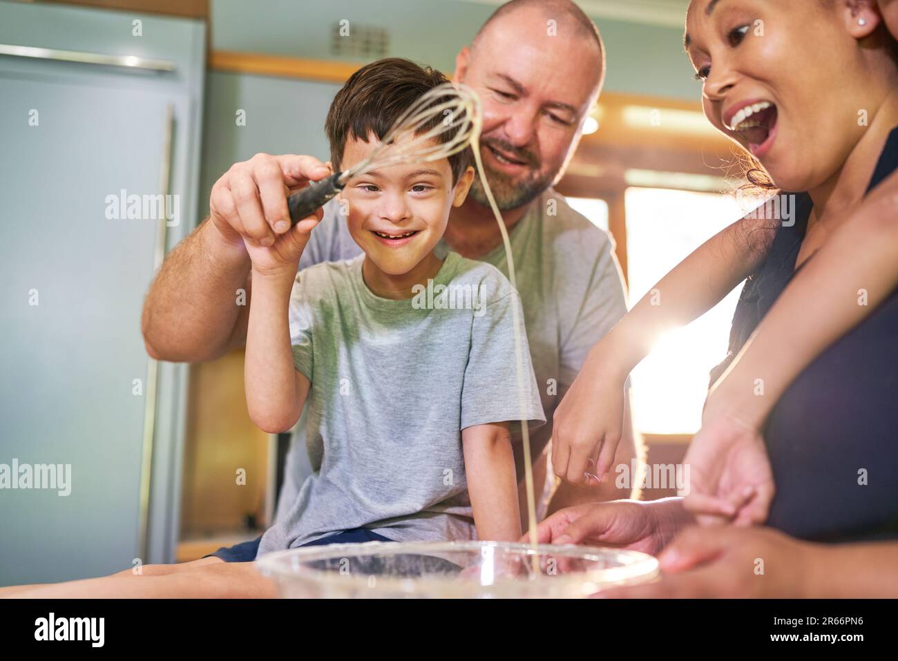 Ragazzo felice con la sindrome di Down cottura con la famiglia a casa Foto Stock