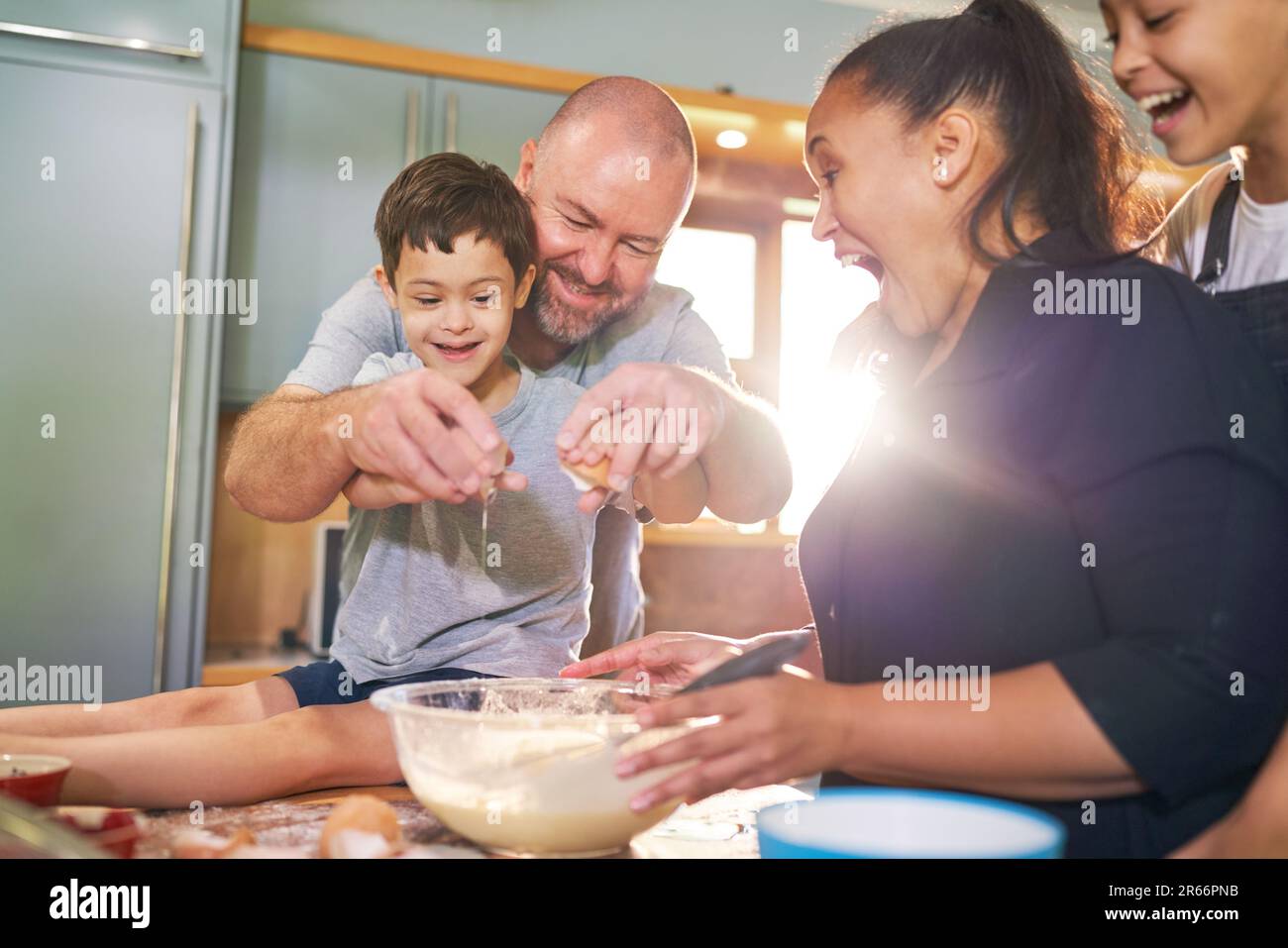 Ragazzo felice con Down sindrome di cottura con la famiglia in cucina Foto Stock