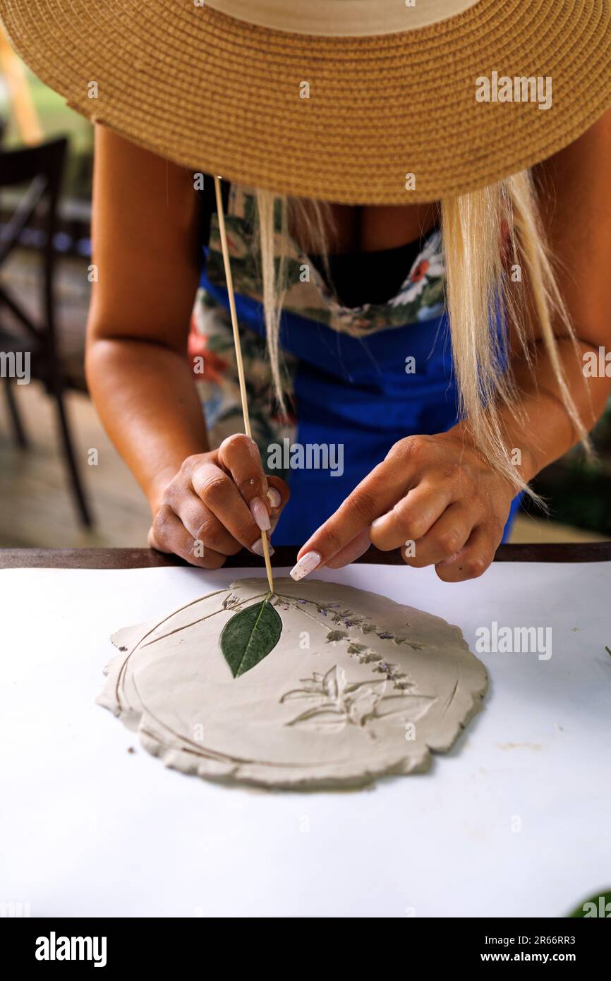 Bella giovane donna fa un'impressione di piante su uno stampo per la produzione di ceramica stencil Foto Stock