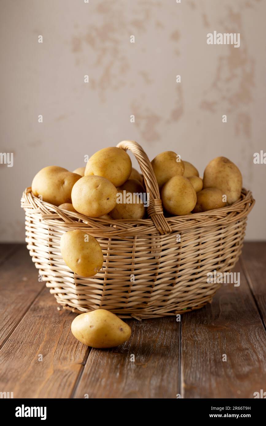 Cestino di vimini con patate su un tavolo di legno marrone con sfondo beige Foto Stock