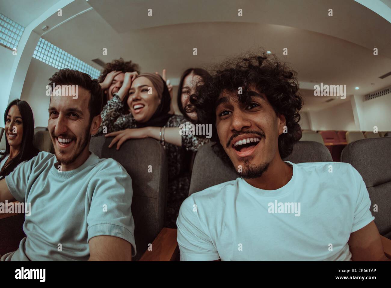 Omedy film, con sorrisi oin un cinema un gruppo diversificato di adolescenti è riunito, guardando un cn loro volti, godendo la risata condivisa e la gioia di Foto Stock