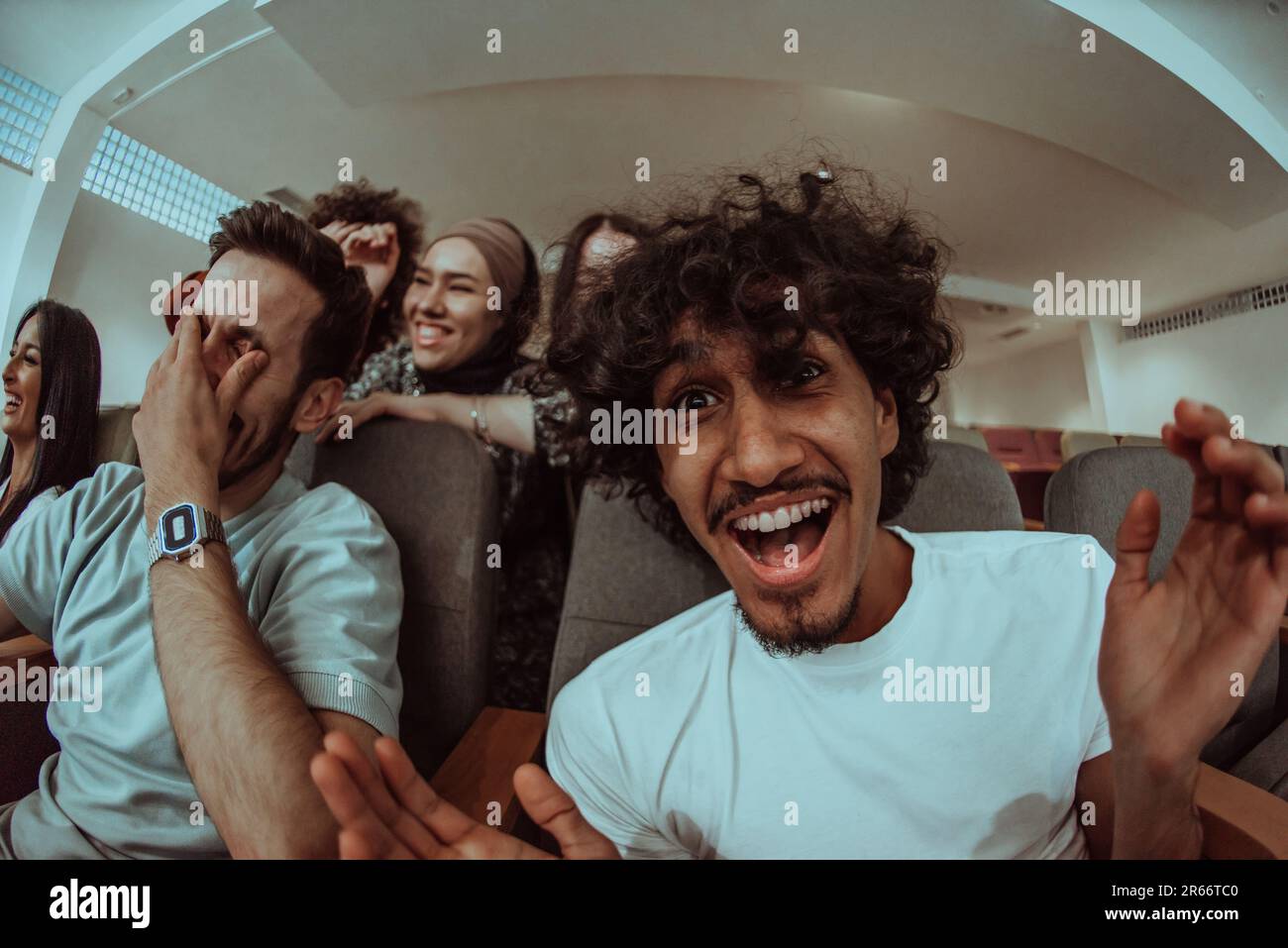 Omedy film, con sorrisi oin un cinema un gruppo diversificato di adolescenti è riunito, guardando un cn loro volti, godendo la risata condivisa e la gioia di Foto Stock