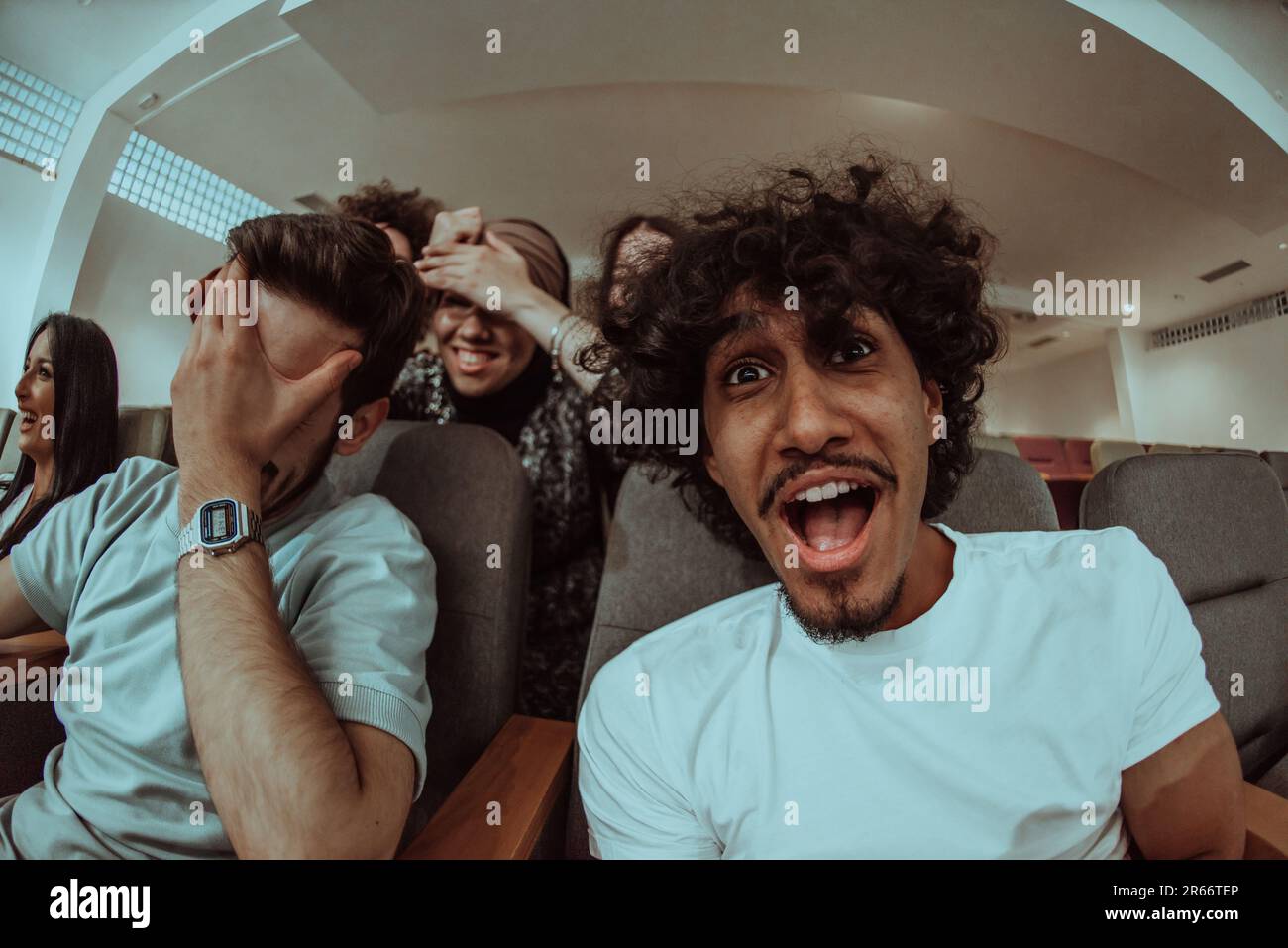 Omedy film, con sorrisi oin un cinema un gruppo diversificato di adolescenti è riunito, guardando un cn loro volti, godendo la risata condivisa e la gioia di Foto Stock