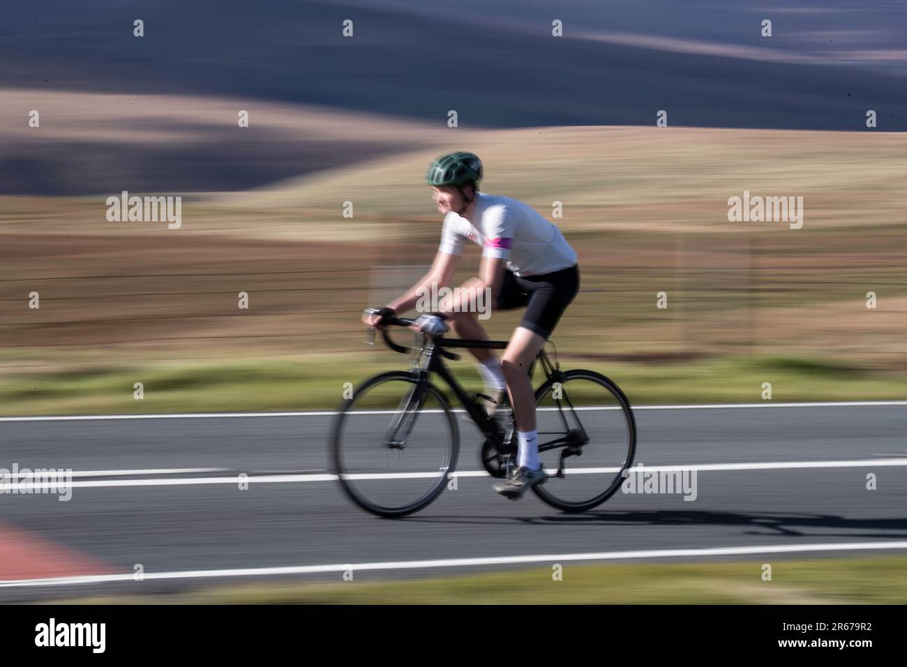 Sfocatura del movimento dei giovani ciclista d'élite che cavalcano a velocità attraverso le orde dello Yorkshire a Wessenden in estate Foto Stock