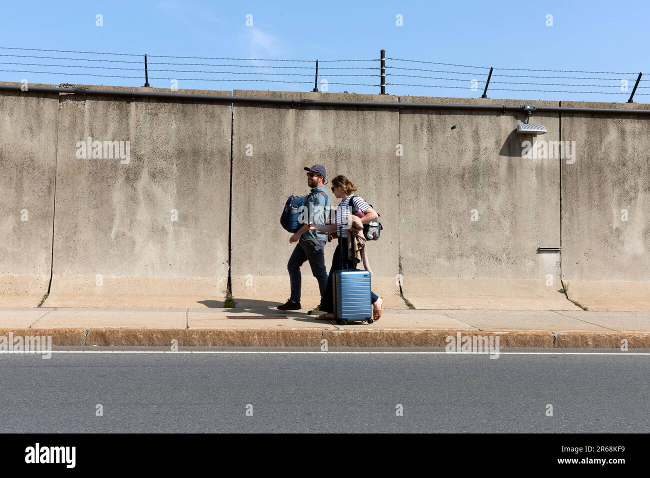 All'aeroporto internazionale Logan, si può fare un paio di bagagli a piedi di fronte a una parete di cemento Foto Stock