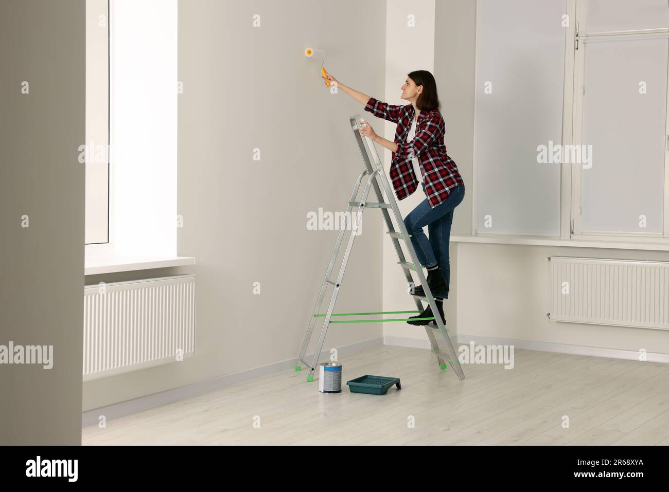 Giovane donna pittura parete con rullo su scala interna. Ristrutturazione  delle camere Foto stock - Alamy