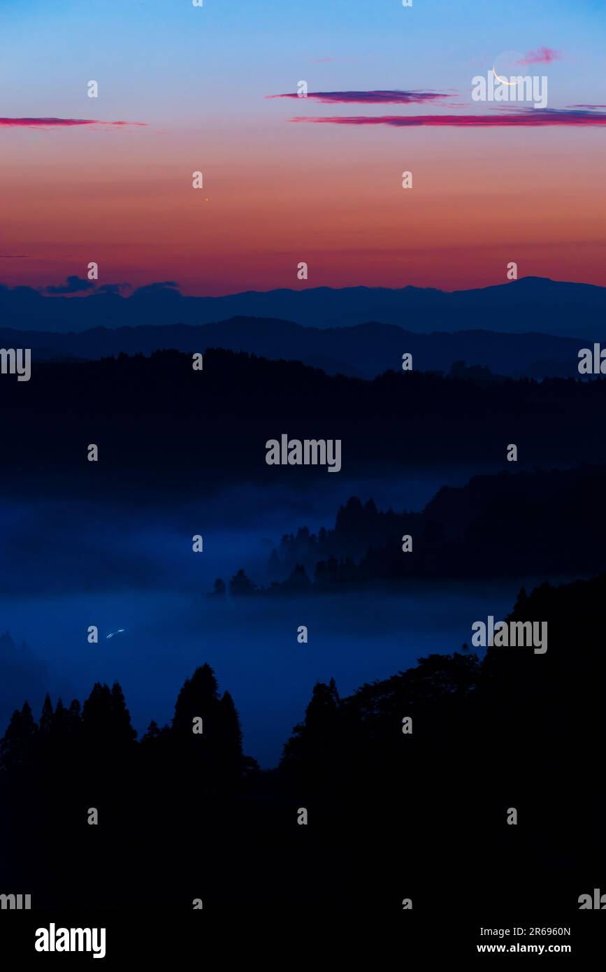 Catena montuosa e luna crescente all'alba Foto Stock