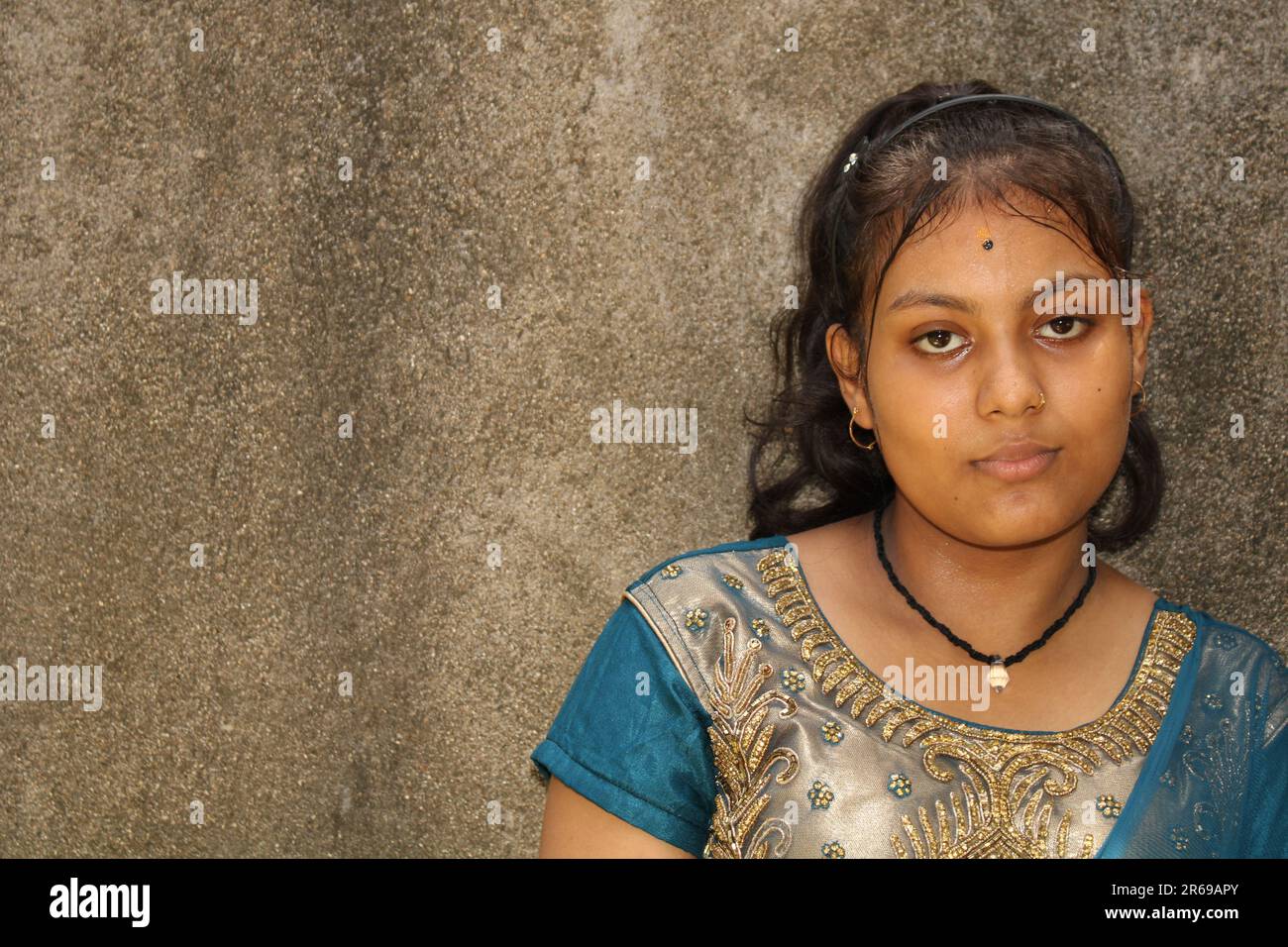 Ritratto di una bella giovane ragazza adolescente, di nazionalità indiana. Sullo sfondo della parete a trama con spazio di copia per testo o parola. All'aperto Foto Stock