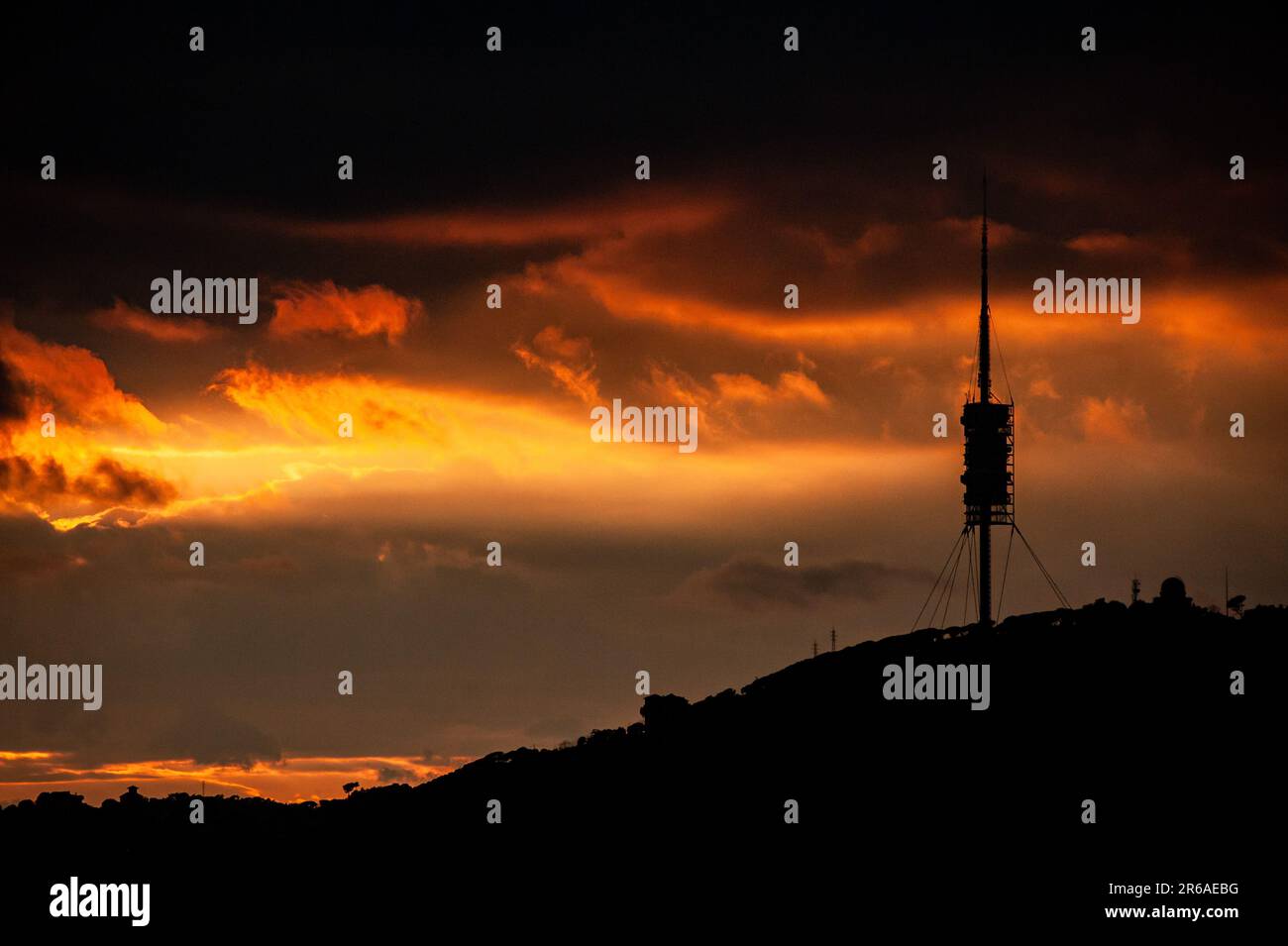 Silhouette della catena Collserola al tramonto, con la Torre de Collserola delineata contro un cielo spettacolare sopra Barcellona, Spagna. Foto Stock