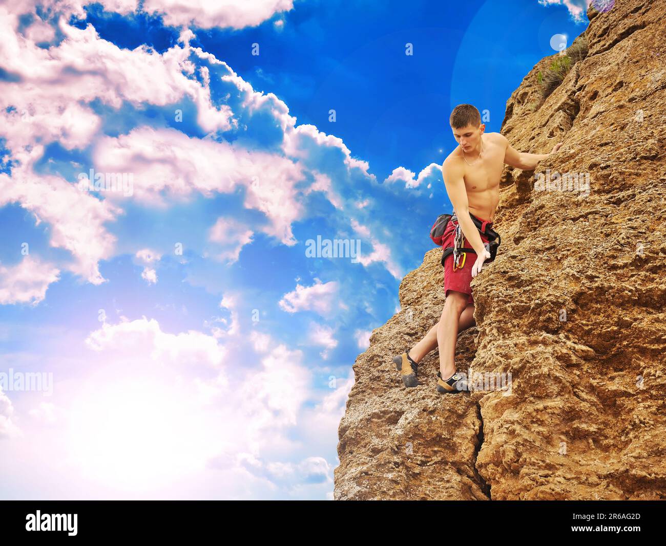 Uomo muscoloso che si arrampica sulla roccia al tramonto Foto Stock