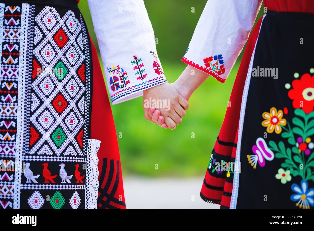 Ragazze in costumi tradizionali etnici bulgari con ricami folcloristici in mano. Lo spirito della Bulgaria - cultura, storia e tradizioni. Foto Stock