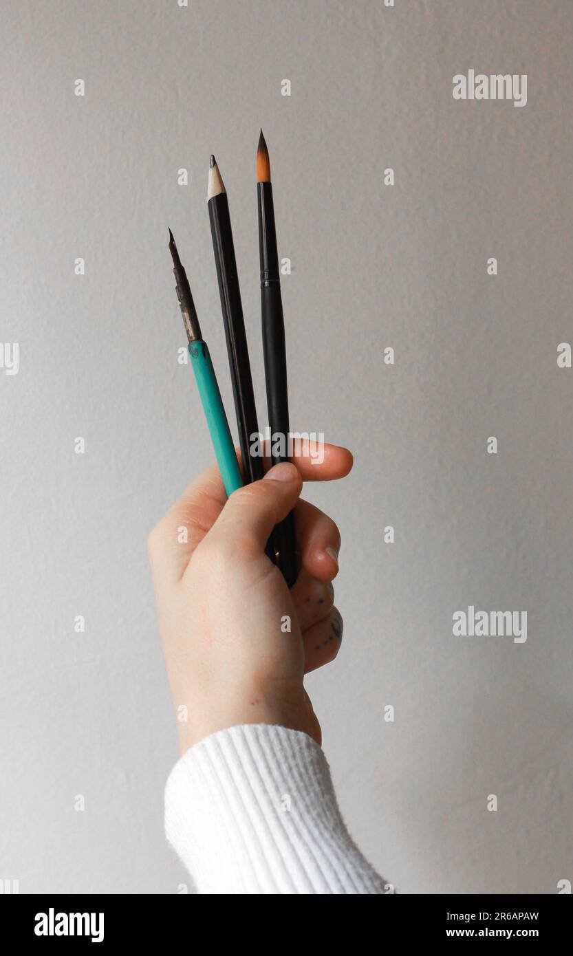 Mani di donna che tengono i pennelli. Concetto di una persona che pensa al suo prossimo pezzo d'arte Concetto di pittura e processo creativo. Foto Stock