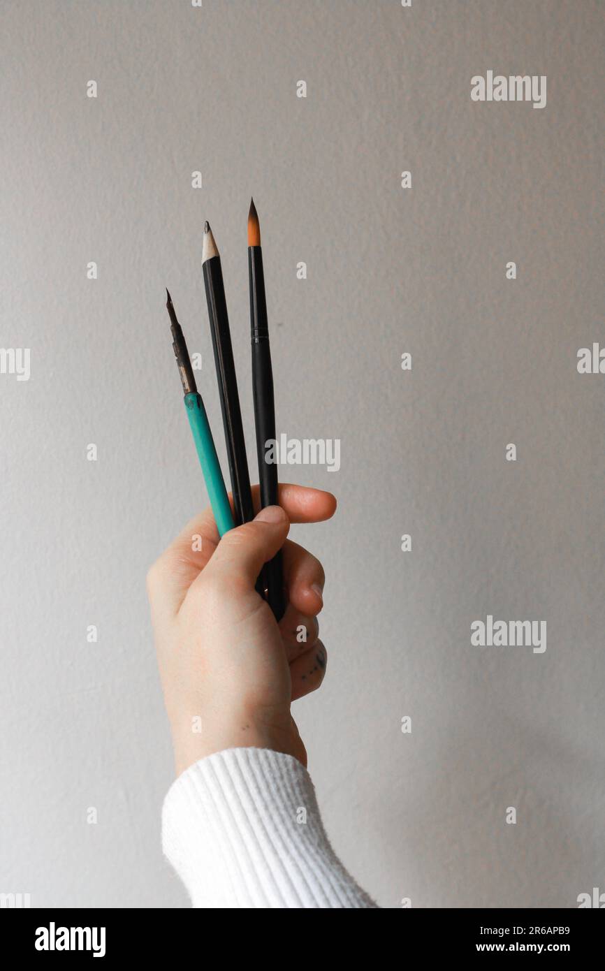 Mani di donna che tengono i pennelli. Concetto di una persona che pensa al suo prossimo pezzo d'arte Concetto di pittura e processo creativo. Foto Stock