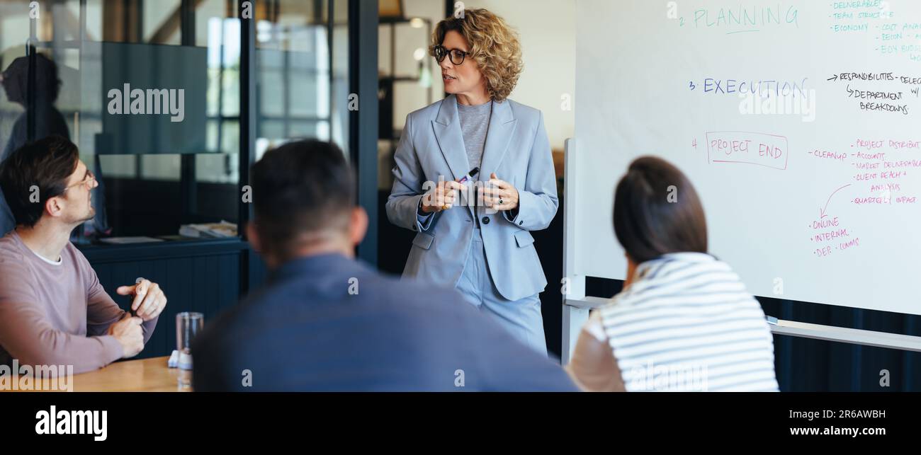 Project manager che ha discusso con il suo team durante una riunione. donna d'affari che tiene una presentazione in una sala riunioni dell'ufficio. Un team di professionisti Foto Stock