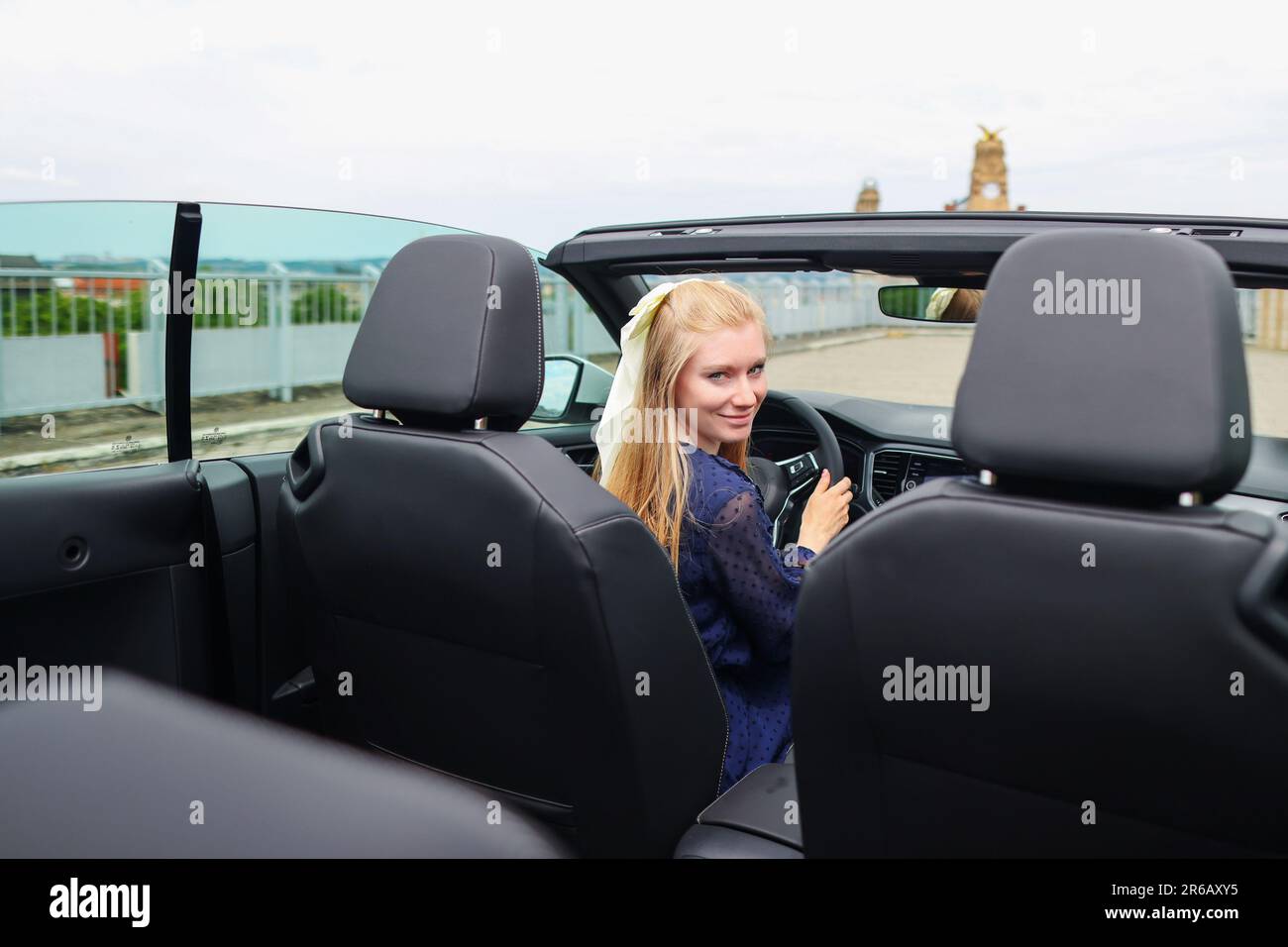 Giovane donna seduta in cabrio e guida in riserva. Foto Stock