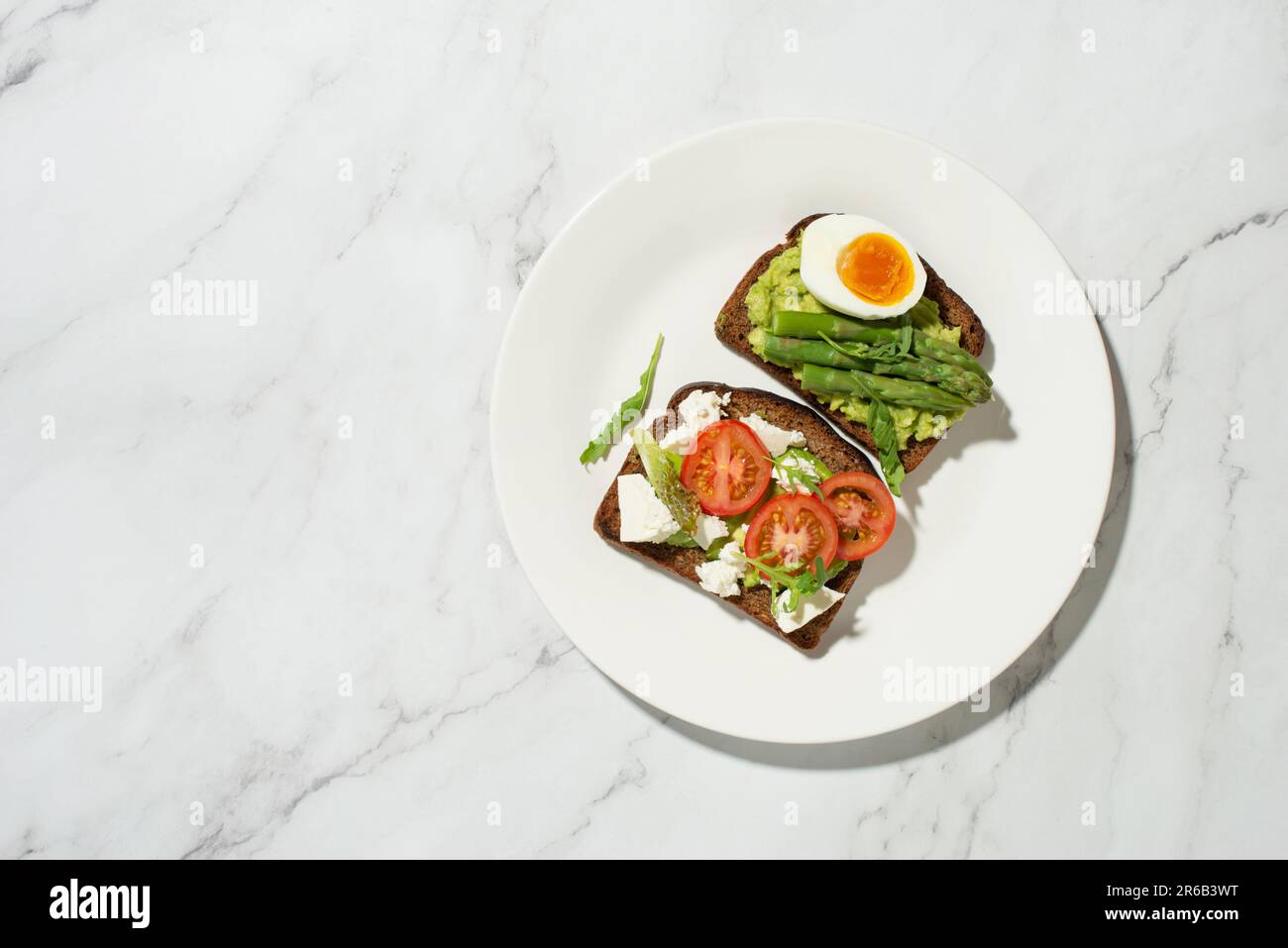 Colazione con toast, avocado, uova e verdure su sfondo grigio Foto Stock