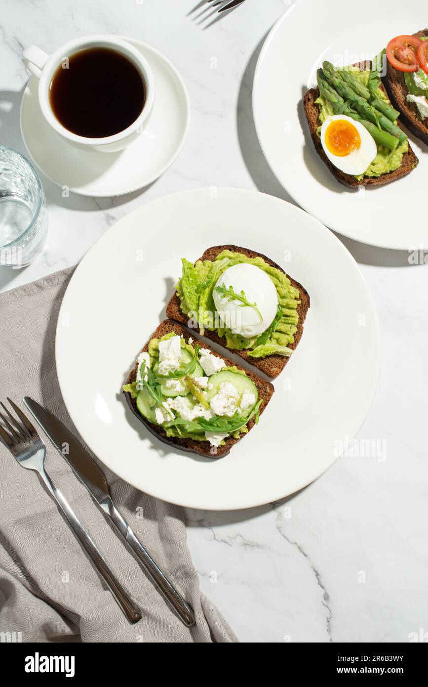 Colazione con toast, avocado, uova e verdure su sfondo grigio Foto Stock