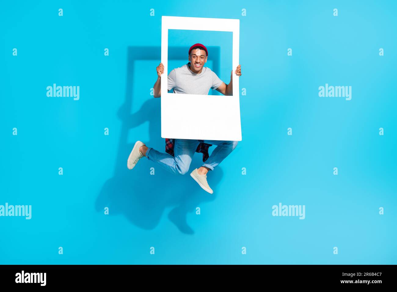 Ritratto a grandezza naturale della persona spensierata attiva che salta le braccia tenere carta album scheda isolato su sfondo di colore blu Foto Stock