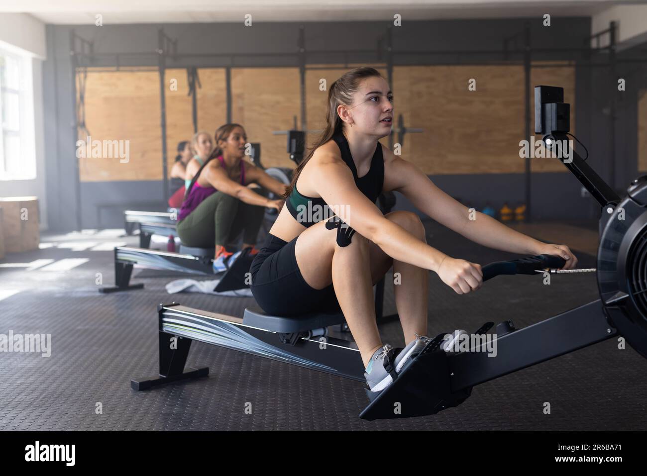 Multirazziale dedicato femmine esercizio su macchine a remi in club benessere, copia spazio Foto Stock