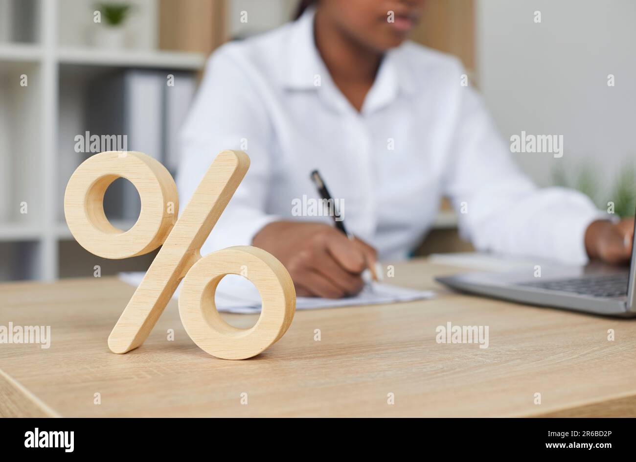 Simbolo di percentuale davanti alla donna d'affari seduta alla scrivania Foto Stock