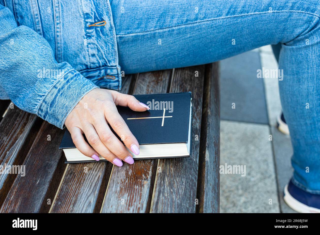 donna che tiene la mano sulla bibbia che giace sulla panchina. donna che tiene carta bibbia. Foto di alta qualità Foto Stock