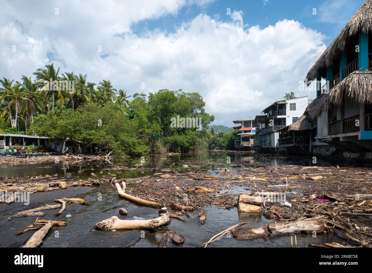 El Tunco, la Libertad, El Salvador - 7 novembre 2022: Foresta tropicale e Hotel rustici sulle rive del fiume con un lotto di legno galleggiante Foto Stock