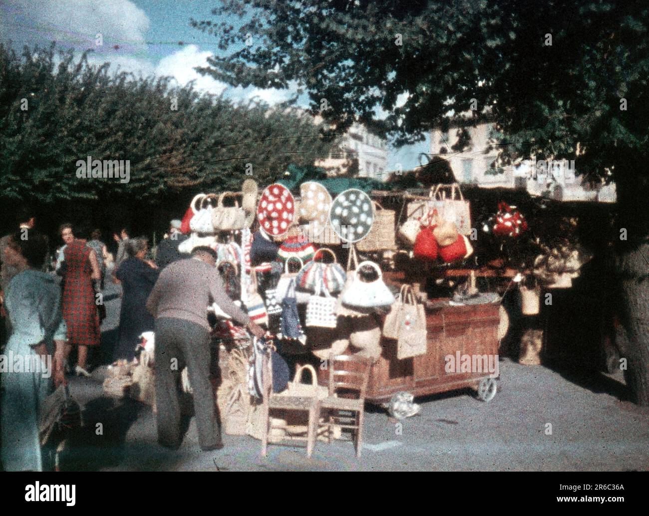 1950s- folle camminano da un fornitore di cappelli e borse tessuti sulla strada della città, artigianato, Minox vintage 8 mm slide scan Foto Stock