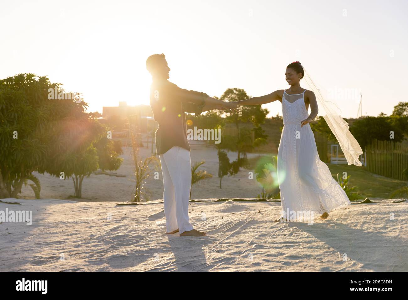 Giovane coppia caucasica appena cucita che balla sulla spiaggia di sabbia contro il cielo limpido al tramonto, copia spazio Foto Stock