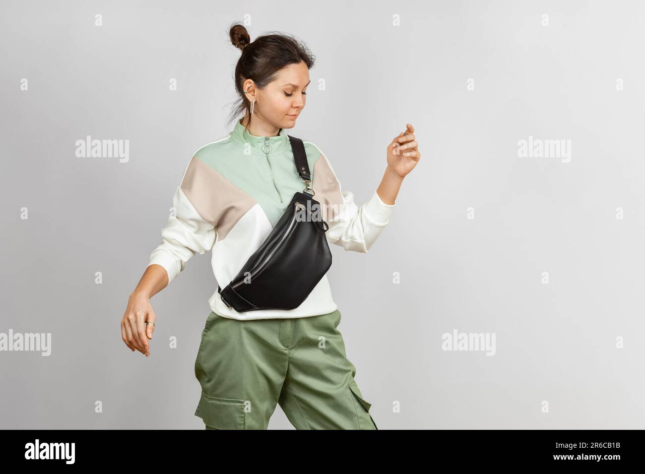 Donna che indossa la tracolla una borsa da cintura in pelle nera su sfondo grigio. Accessori in pelle fatti a mano Foto Stock