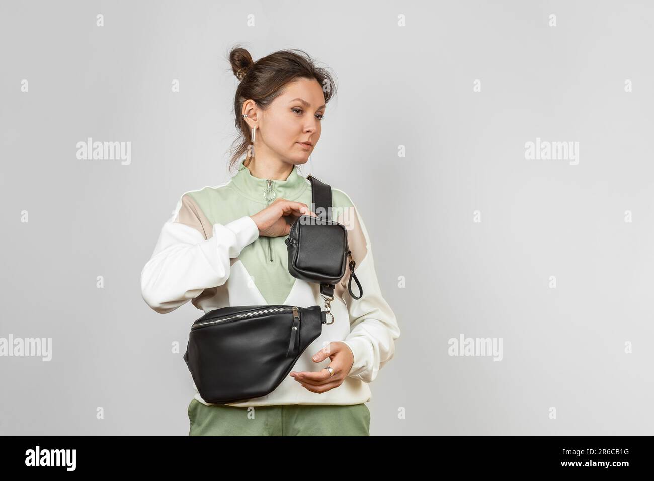 Donna che indossa una borsa in pelle nera in vita con un accessorio portamonete rimovibile per riporre chiavi, sigaretta o auricolari attaccati alla tracolla, Studio Shot Foto Stock