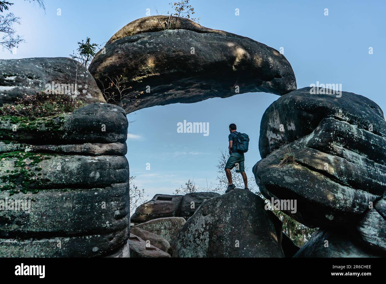 Uomo zaino in spalla in Rock Gate nella riserva naturale Broumov muri, Czech Republic.Old arenaria formazione di roccia in Broumovske steny.Active viaggiatore maschio Foto Stock