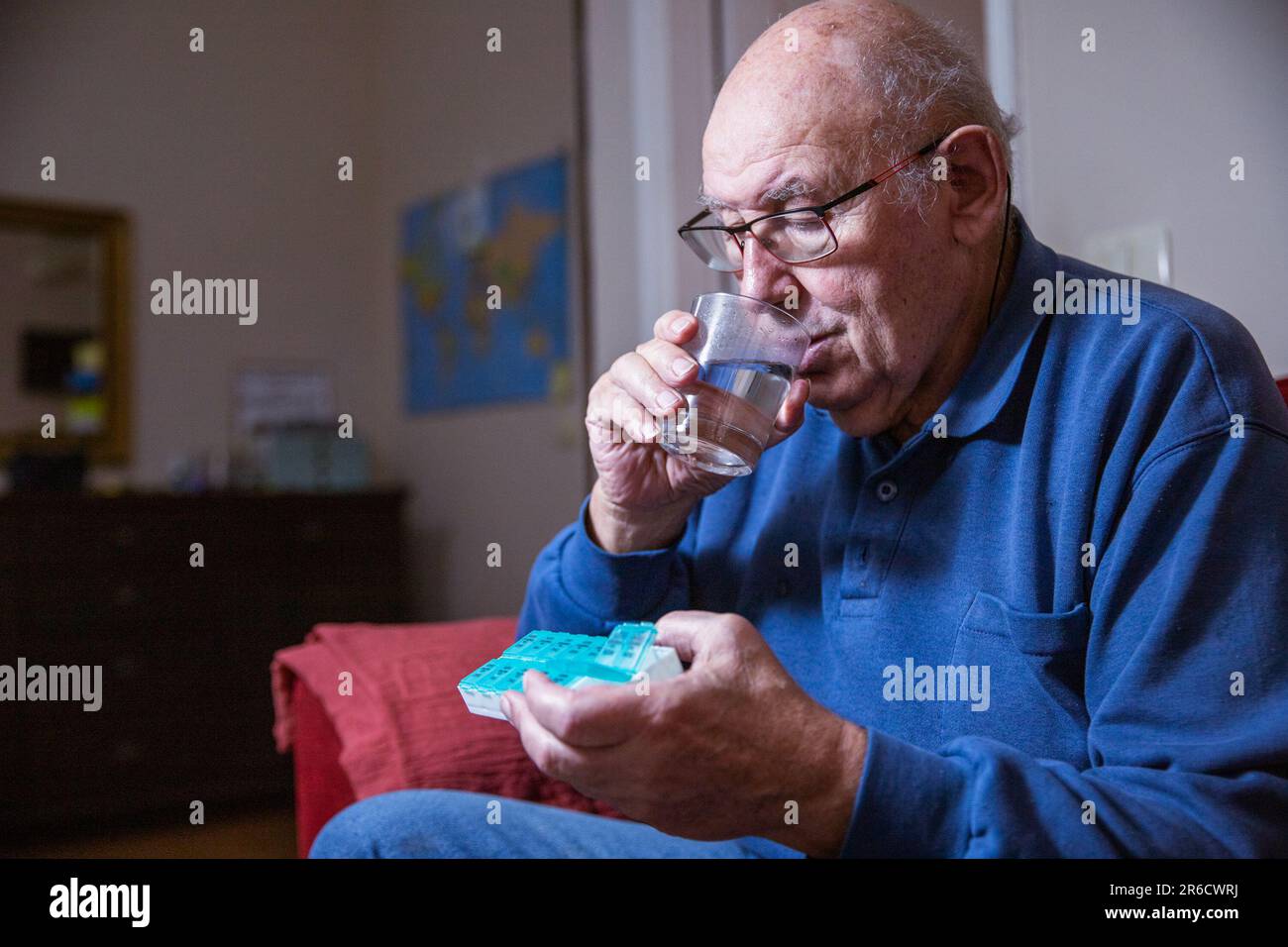 Un uomo anziano prende il suo farmaco mentre a casa, assistenza sanitaria a casa. Foto Stock