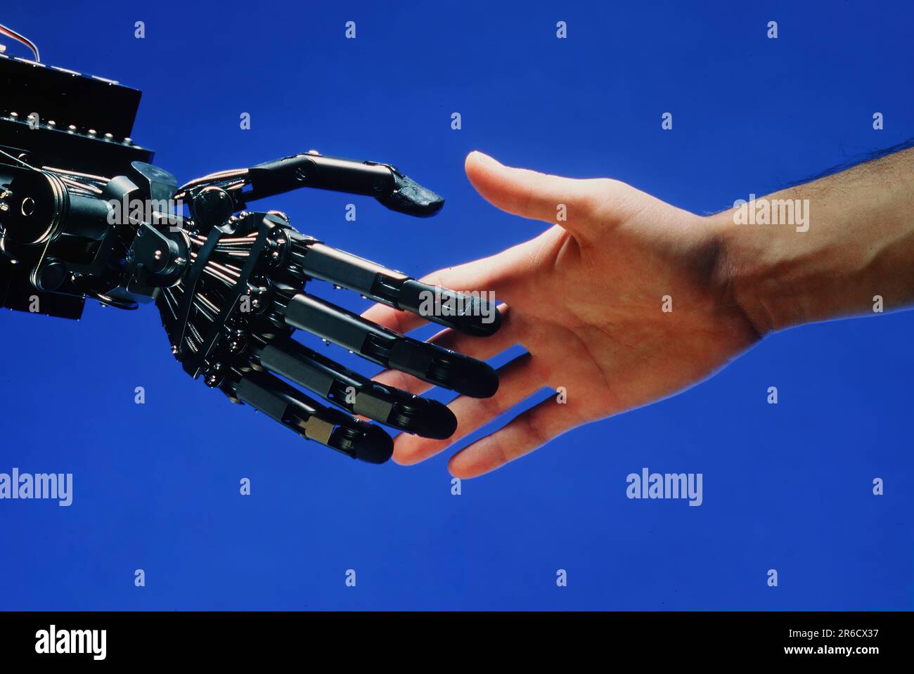 Un essere umano scuote le mani con un robot Foto Stock