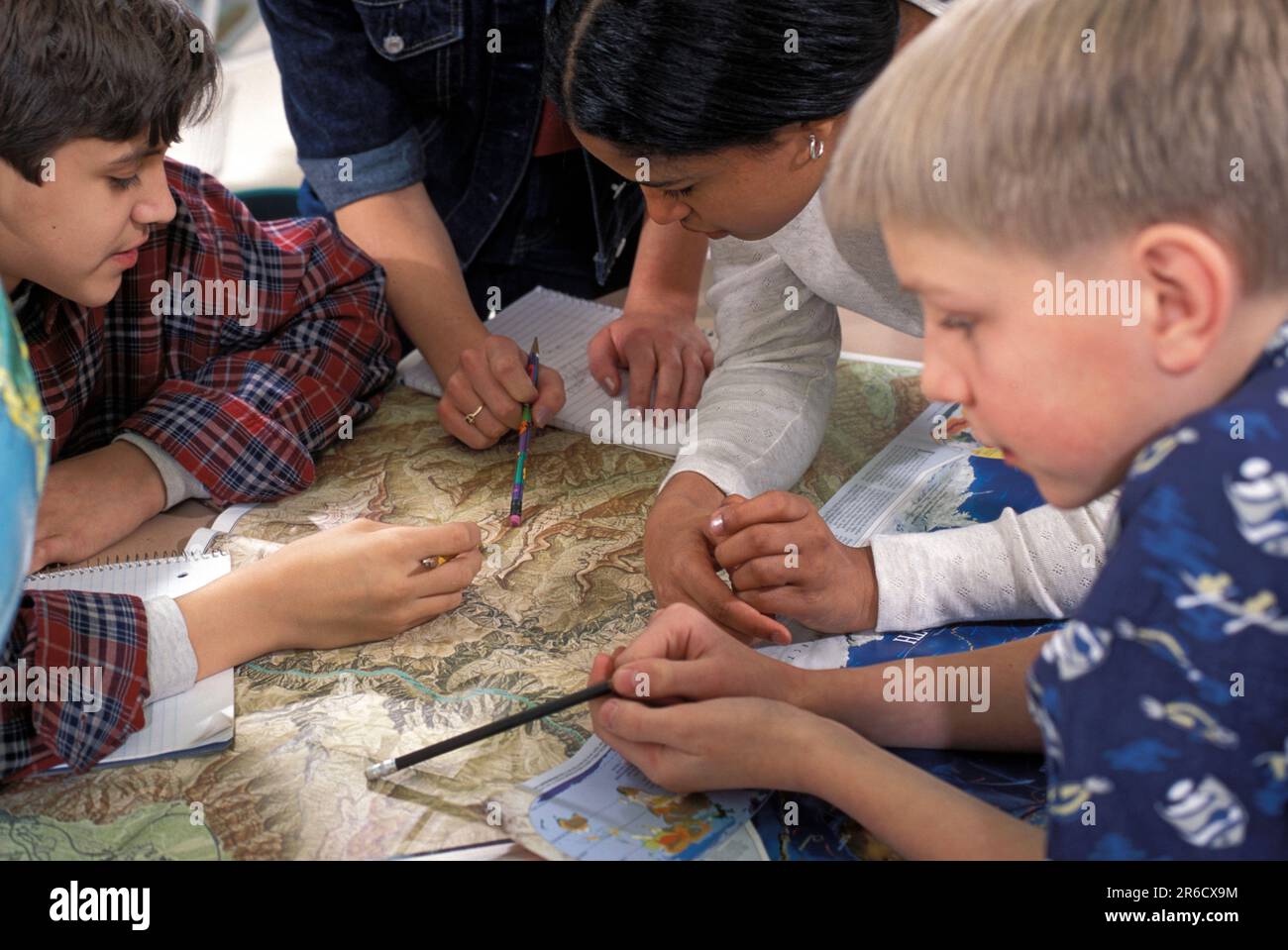 gruppo di studenti della scuola media che usano le mappe durante una lezione di geografia a scuola Foto Stock