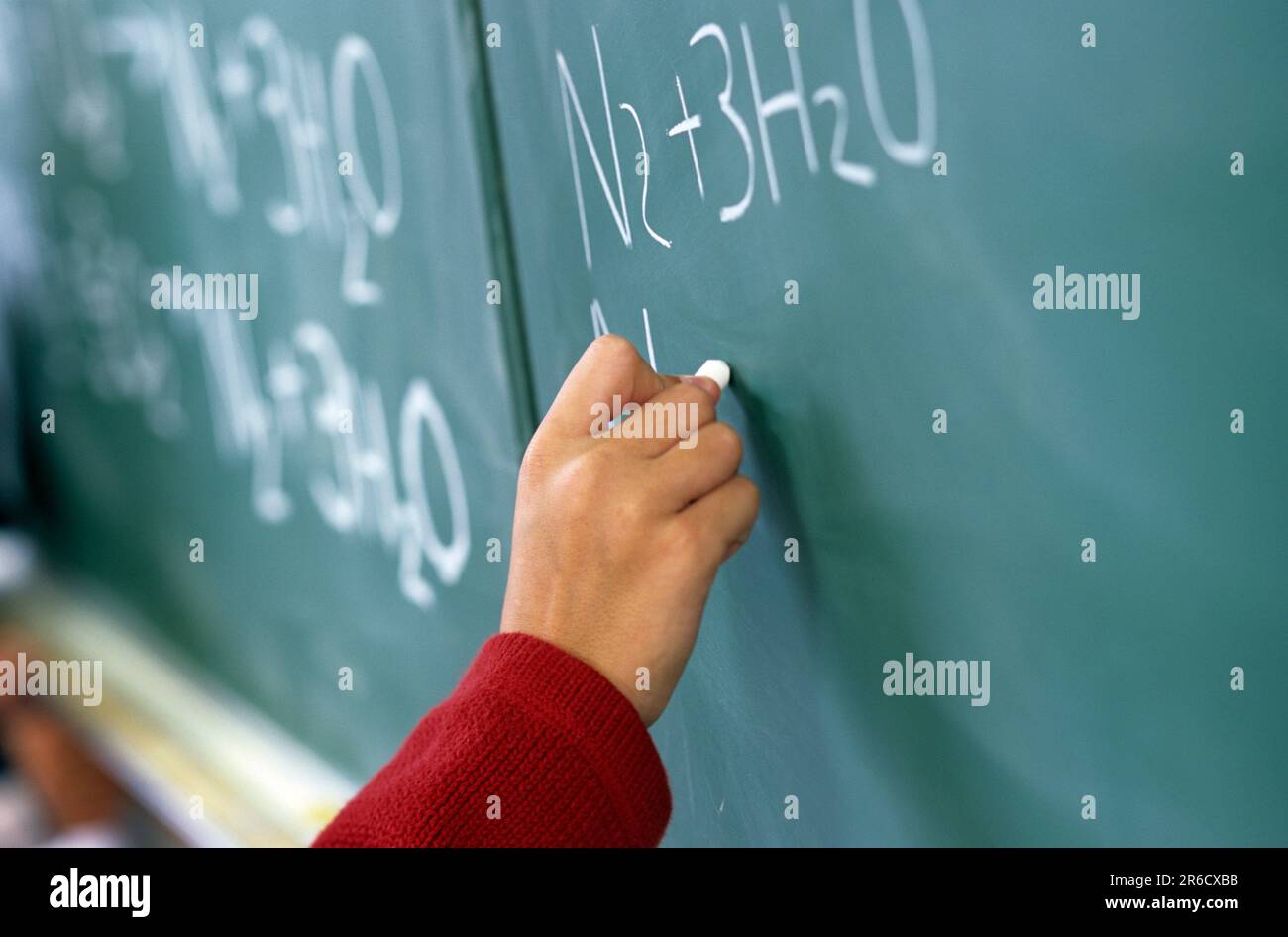allievo che completa un incarico scientifico sulla lavagna della scuola Foto Stock